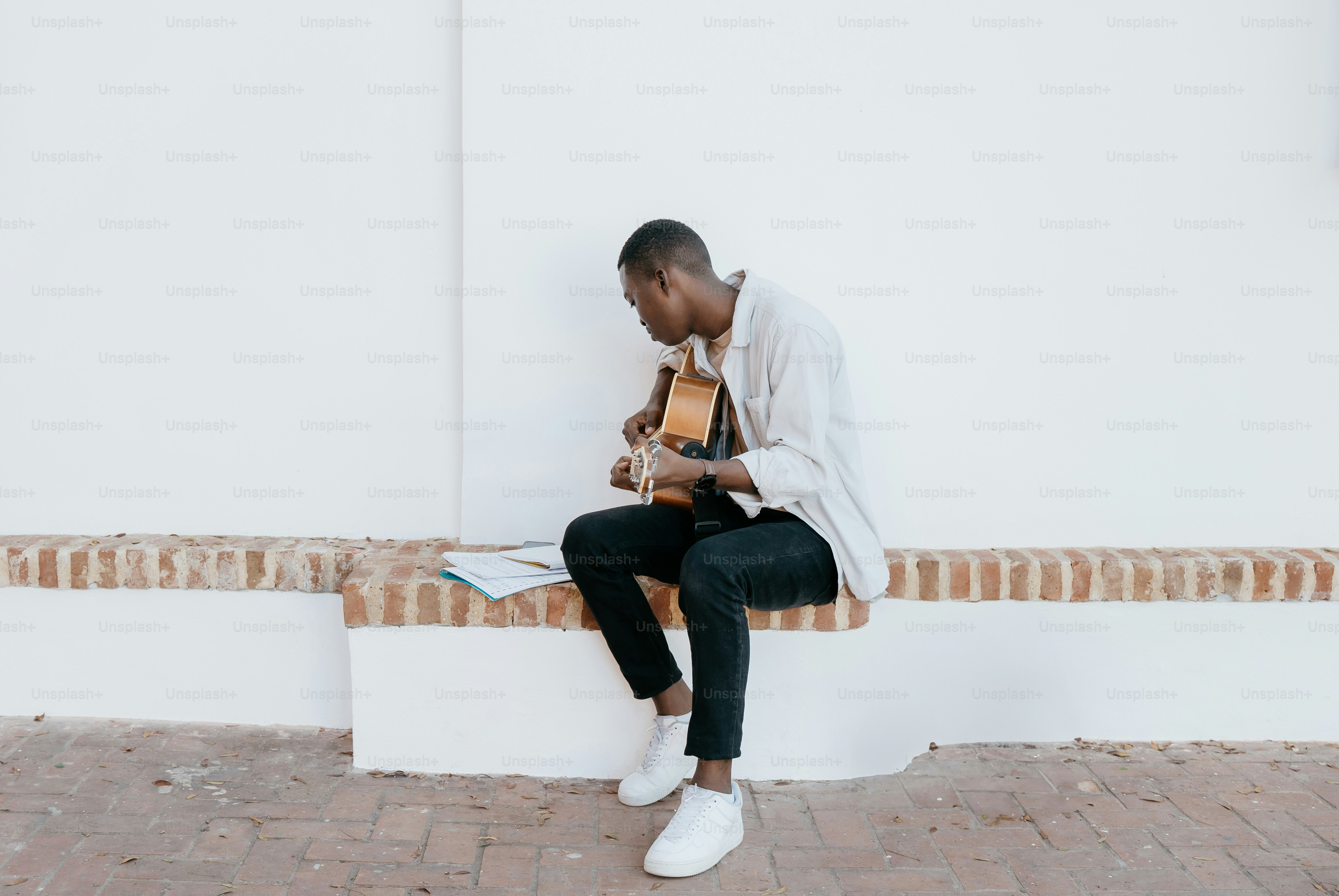 a man sitting on a bench playing a guitar