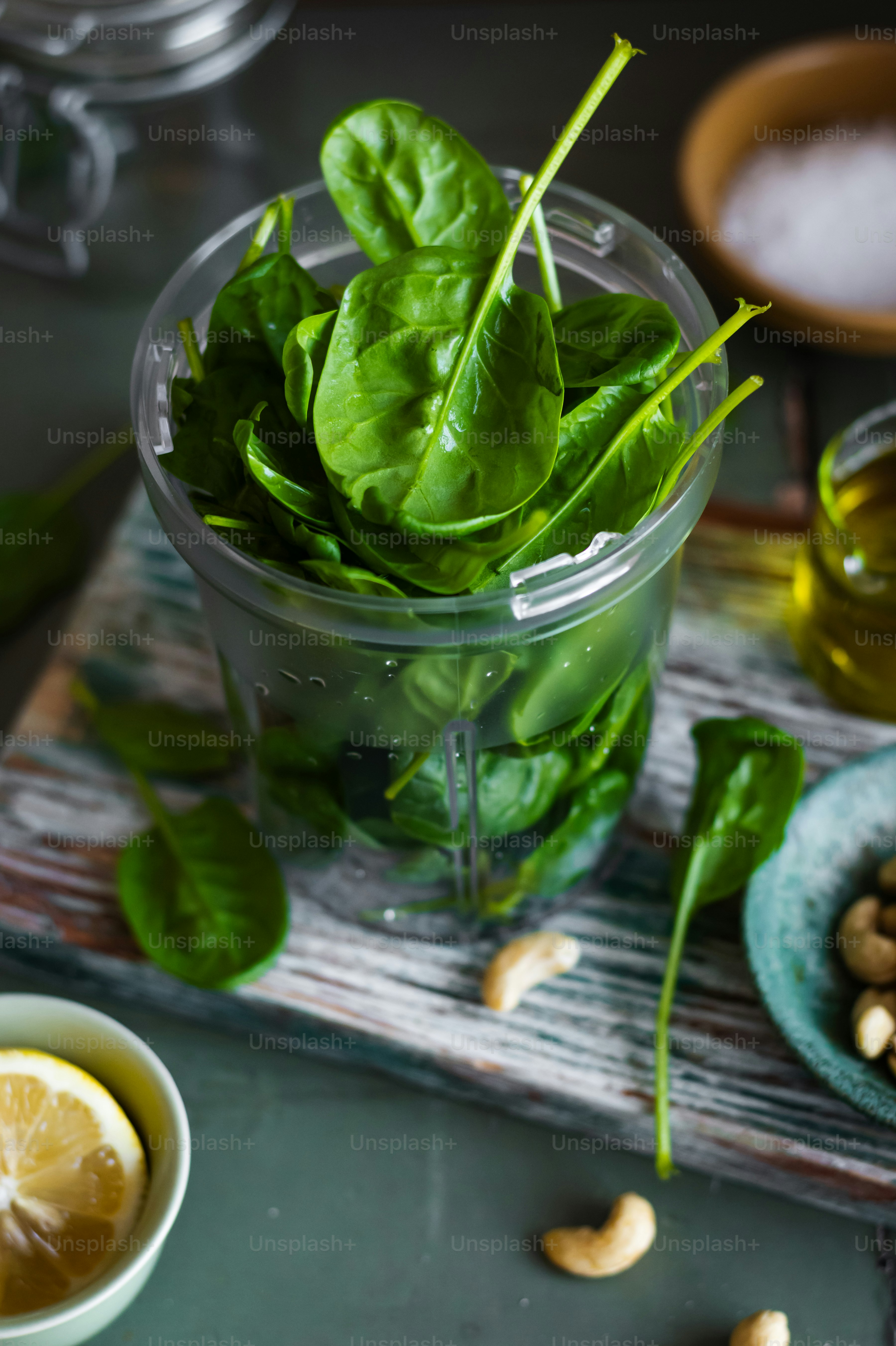 a bowl of spinach leaves next to a bowl of cashews