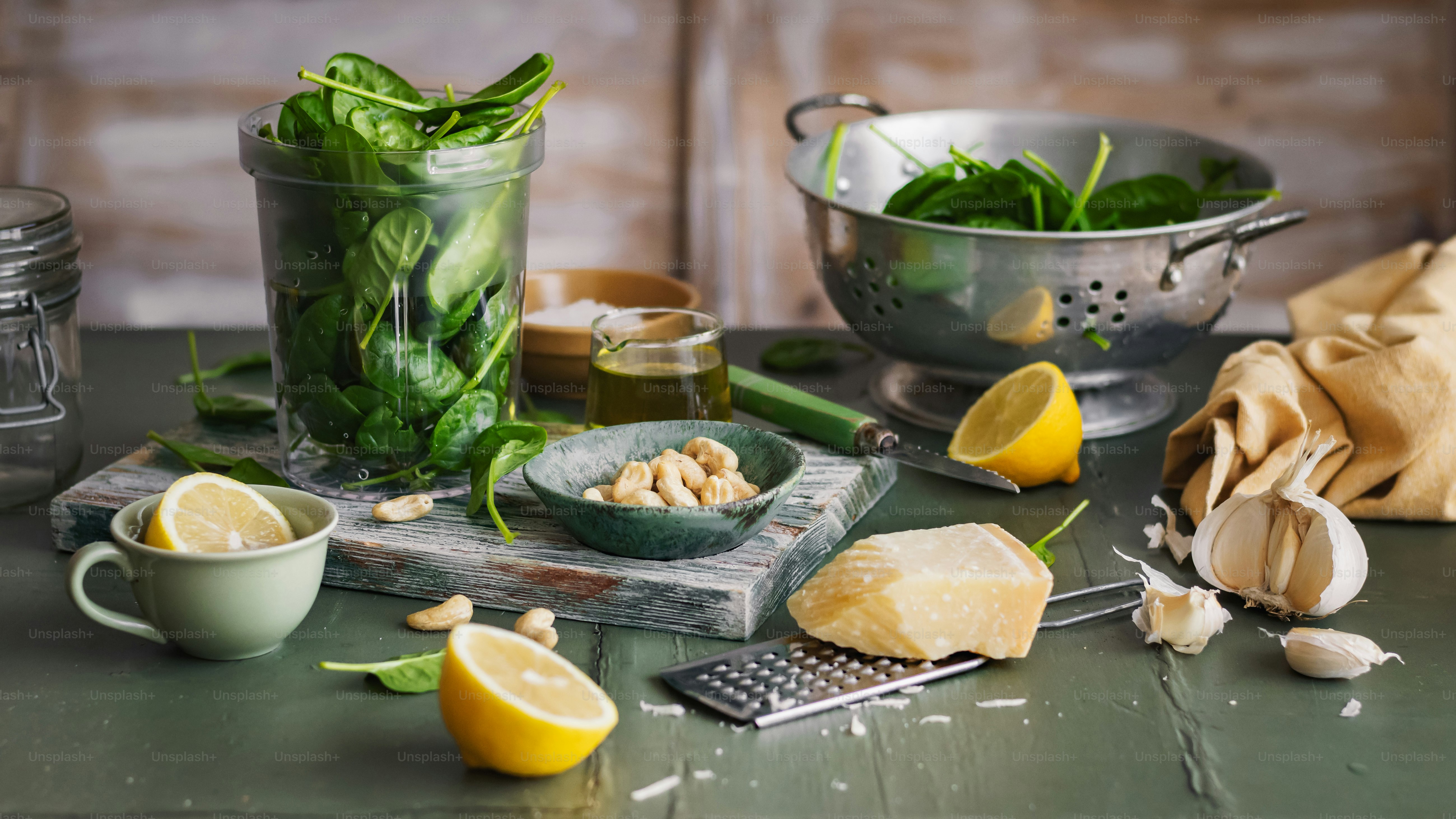 a table topped with a bowl of spinach next to a bowl of lemons