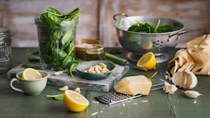 a table topped with a bowl of spinach next to a bowl of lemons