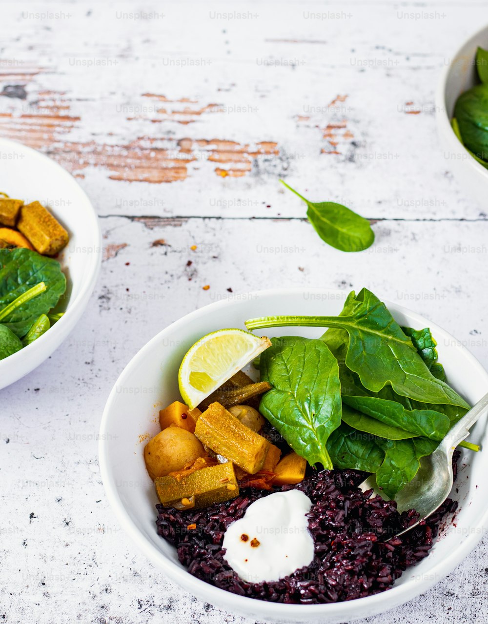 two bowls of food with spinach, tofu, and other vegetables