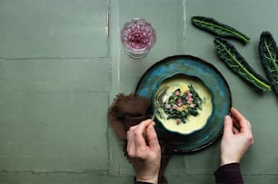 a person holding a bowl of soup on a plate