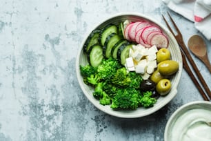 a bowl of vegetables with olives, cucumbers and cheese
