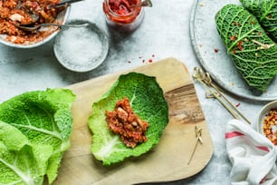 a wooden cutting board topped with lettuce covered in sauce