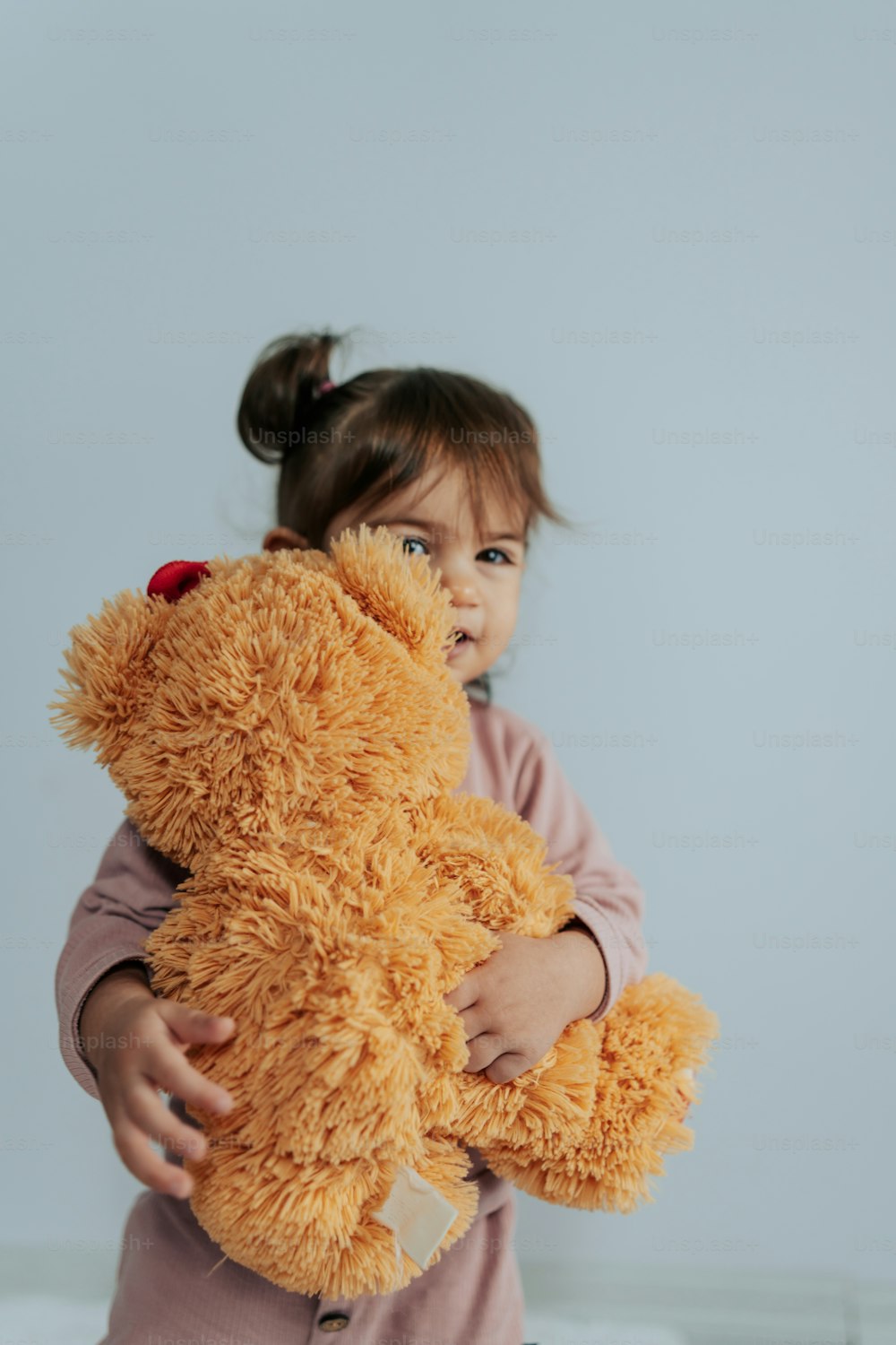 uma menina segurando um ursinho de pelúcia em seus braços