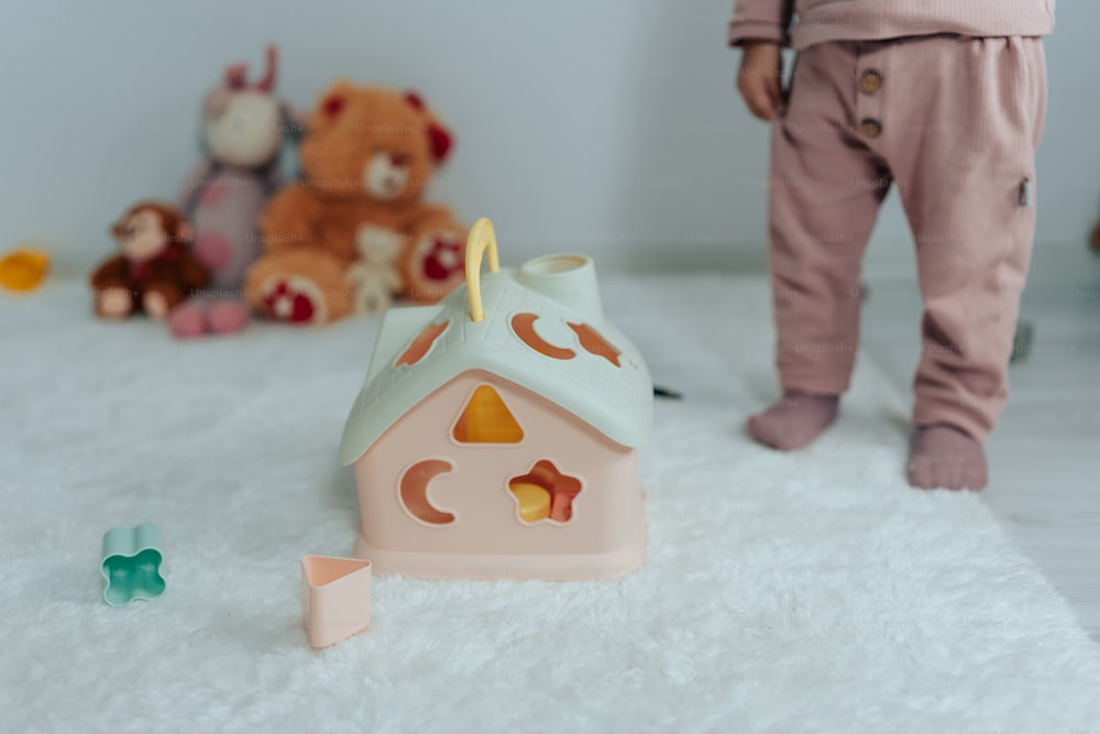Un niño pequeño de pie junto a una casa de juguete