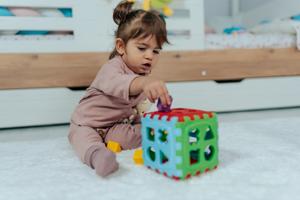 una bambina che gioca con un giocattolo sul pavimento