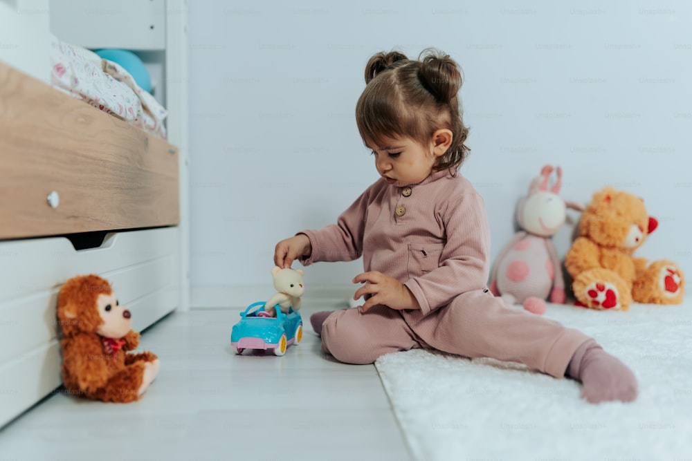 une petite fille assise sur le sol jouant avec un jouet