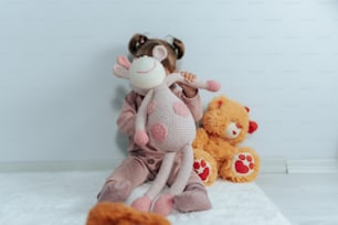 a little girl sitting next to two stuffed animals