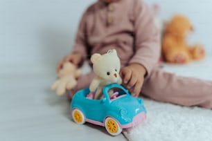 a little girl sitting on the floor playing with a teddy bear