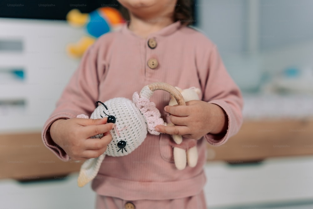 una niña pequeña sosteniendo un animal de peluche en sus manos