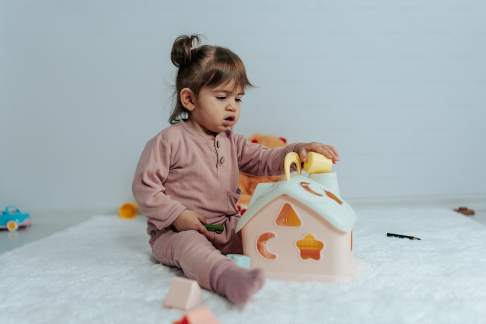 a little girl sitting on the floor playing with a toy