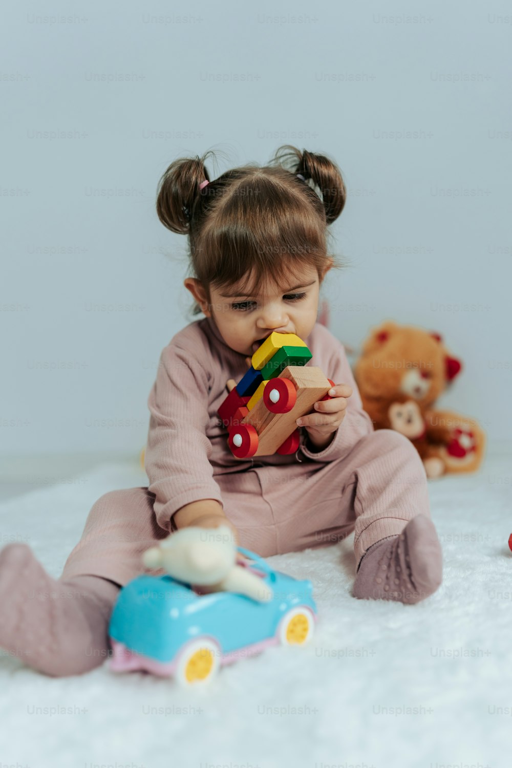 a little girl sitting on a bed playing with a toy