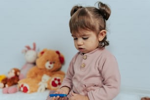 a little girl sitting on the floor playing with a toy