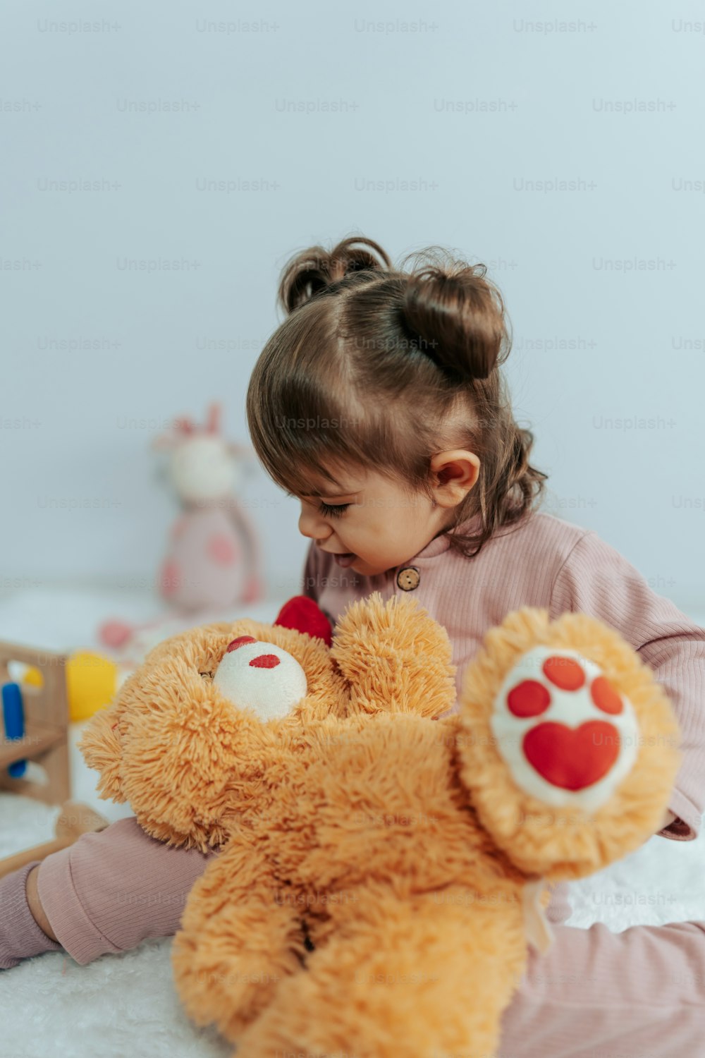 a little girl playing with a teddy bear