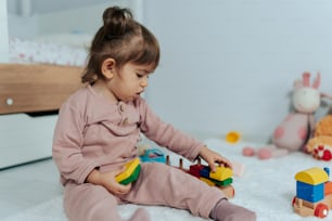 ein kleines Mädchen, das auf dem Boden sitzt und mit einem Spielzeug spielt