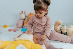 a little girl sitting on the floor playing with a stuffed animal
