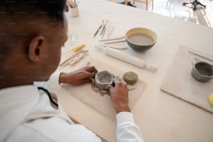 a man in a white shirt is working on a piece of pottery