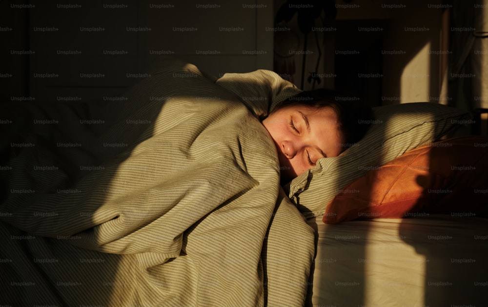 a woman is sleeping in a bed with a blanket