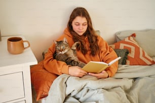 a woman reading a book while holding a cat