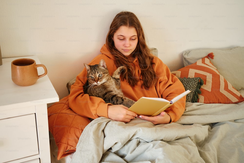 a woman reading a book while holding a cat