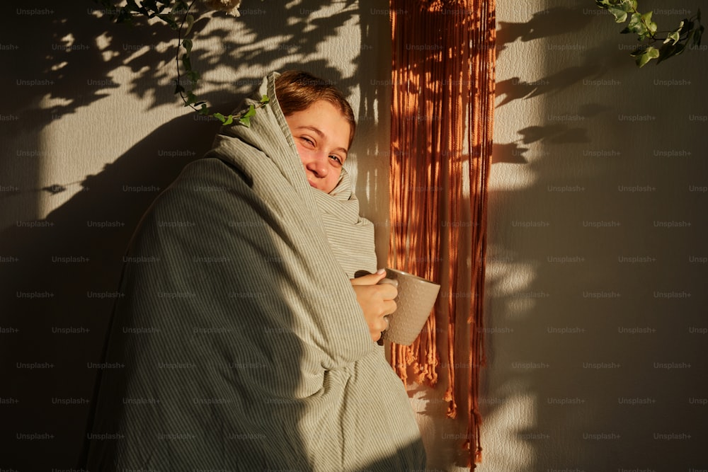 Uma mulher enrolada em um cobertor está sorrindo