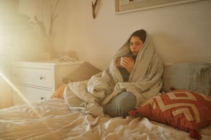 a woman wrapped in a blanket sitting on a bed