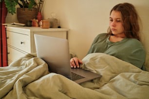 a woman laying in bed using a laptop computer