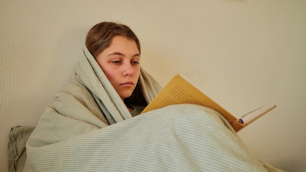 a woman wrapped in a blanket reading a book