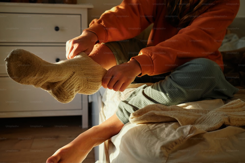 a person sitting on a bed with a pair of socks