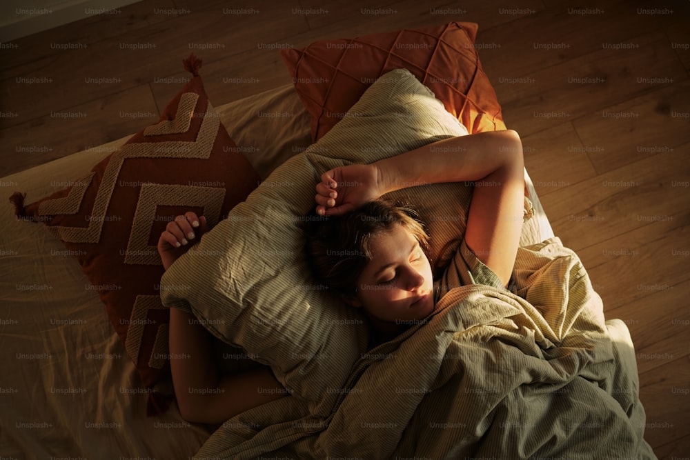 a woman laying in bed with her head on a pillow