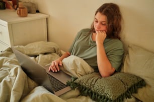 a woman sitting on a bed using a laptop computer