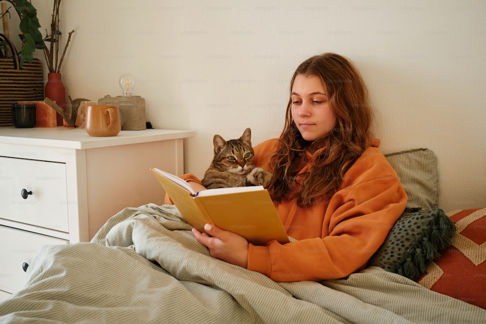 a woman reading a book with a cat on her lap