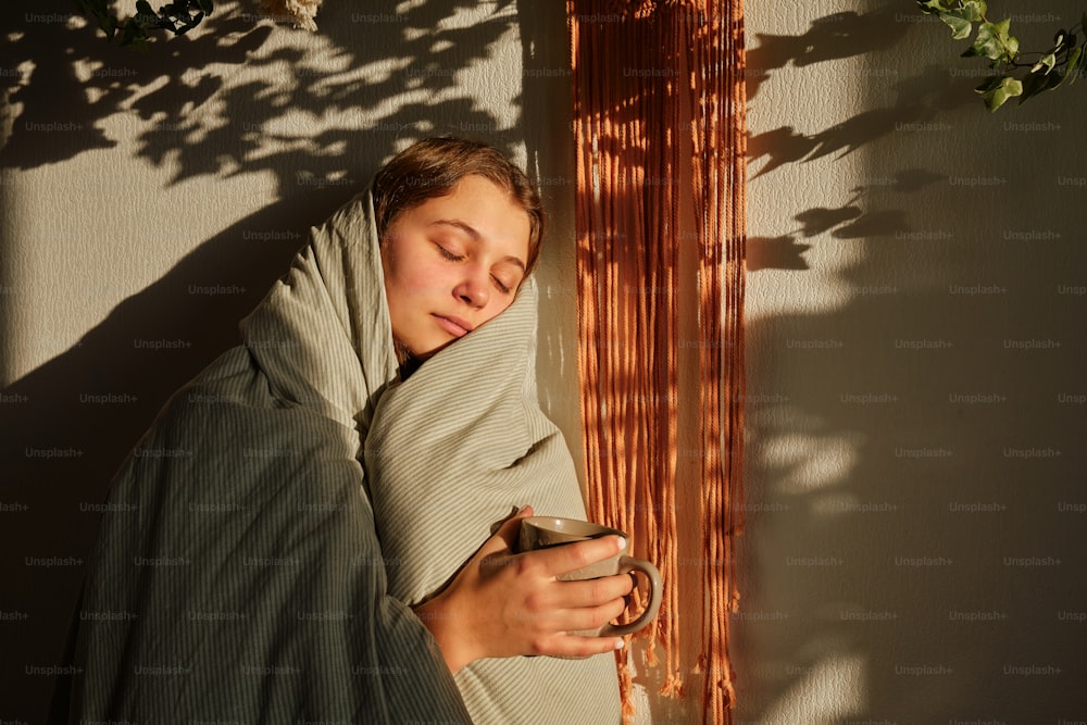 Una donna avvolta in una coperta tiene in mano una tazza
