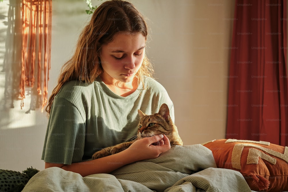 a woman holding a cat while sitting on a bed