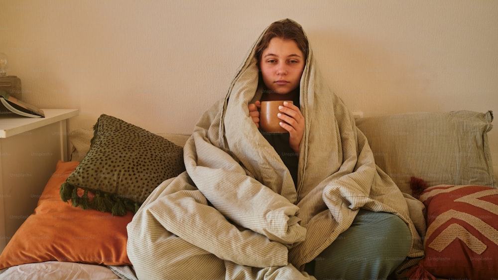a woman wrapped in a blanket holding a cup of coffee