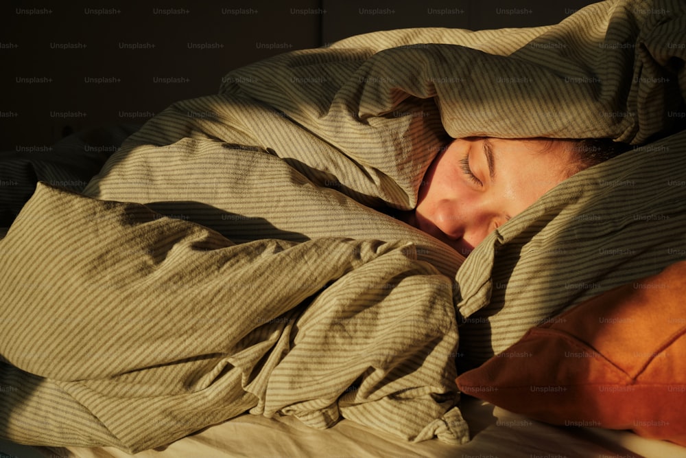 una mujer durmiendo en una cama bajo una manta