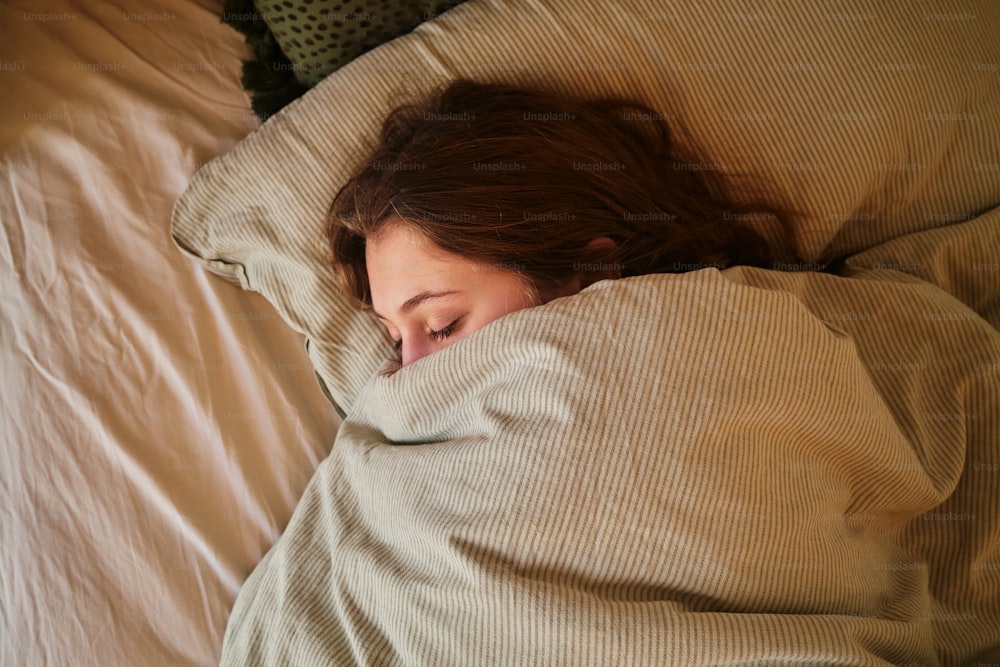 a woman sleeping in a bed under a blanket