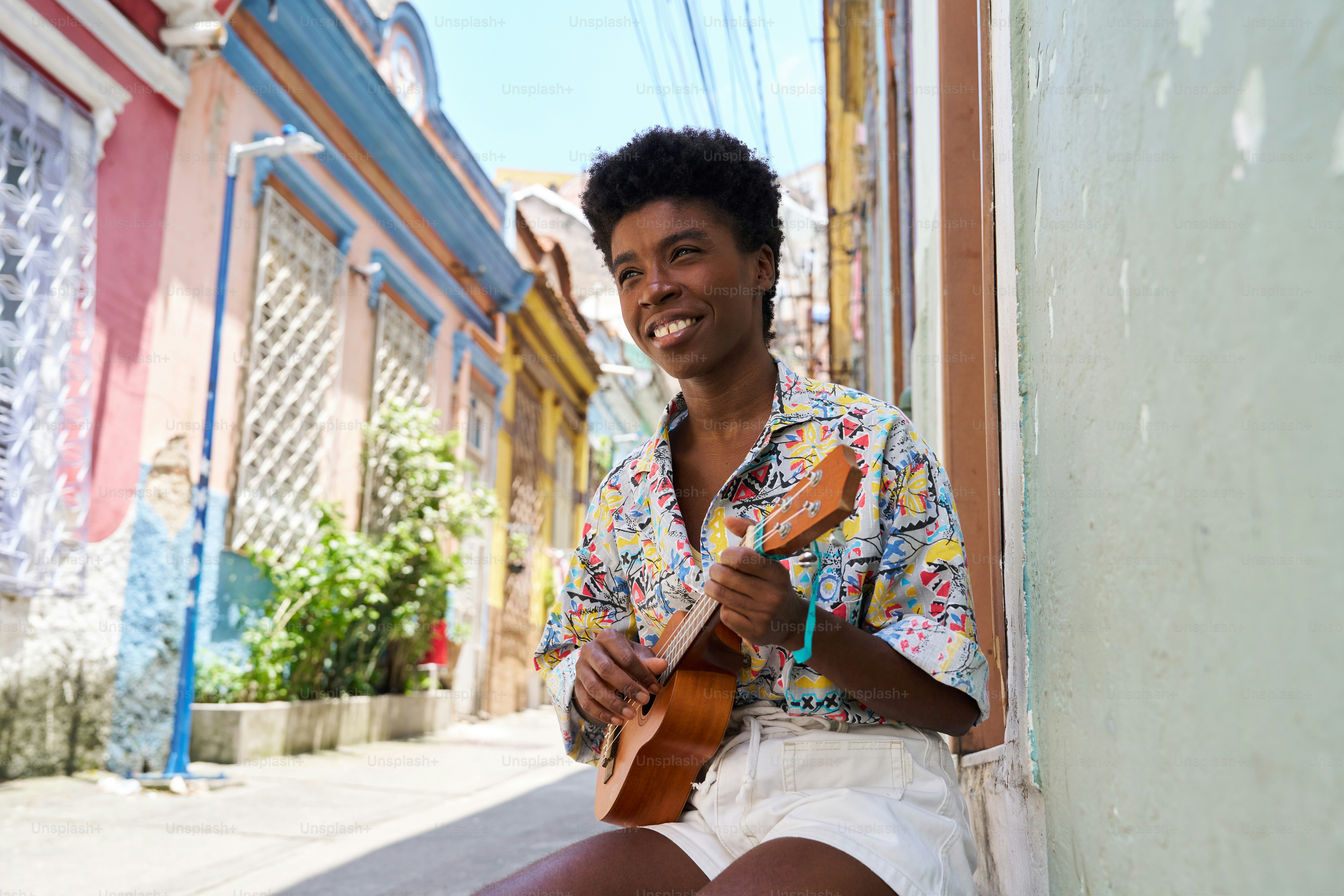 a man sitting on the side of a building holding a guitar