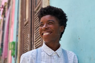a smiling young man standing in front of a blue wall