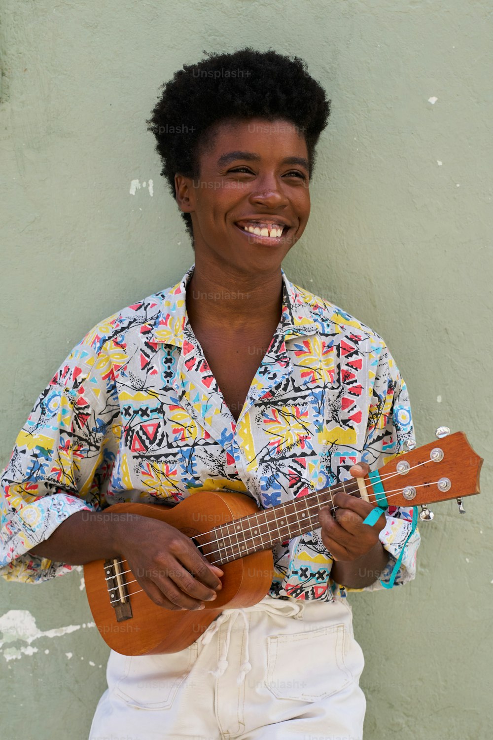 a man is smiling while holding a guitar