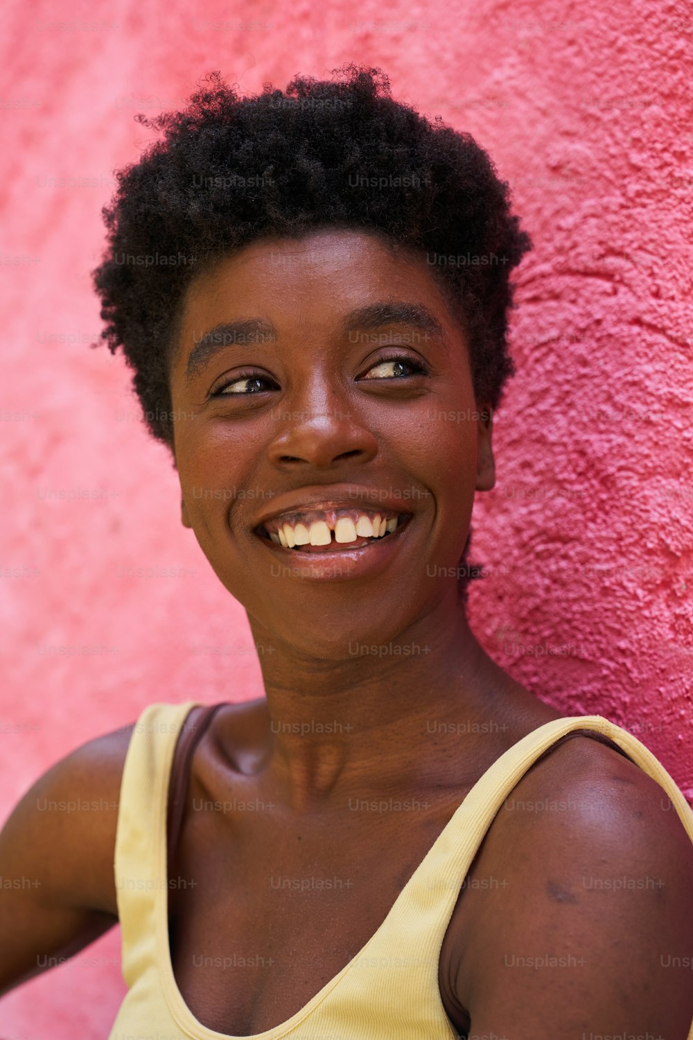 a woman smiling in front of a pink wall