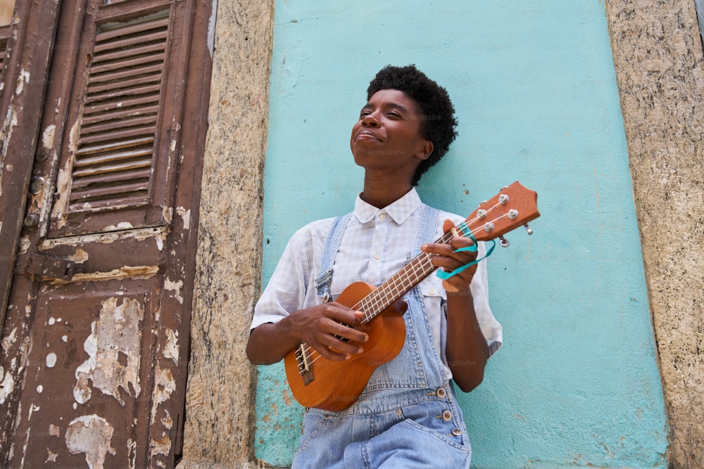 a man holding a guitar in front of a blue wall