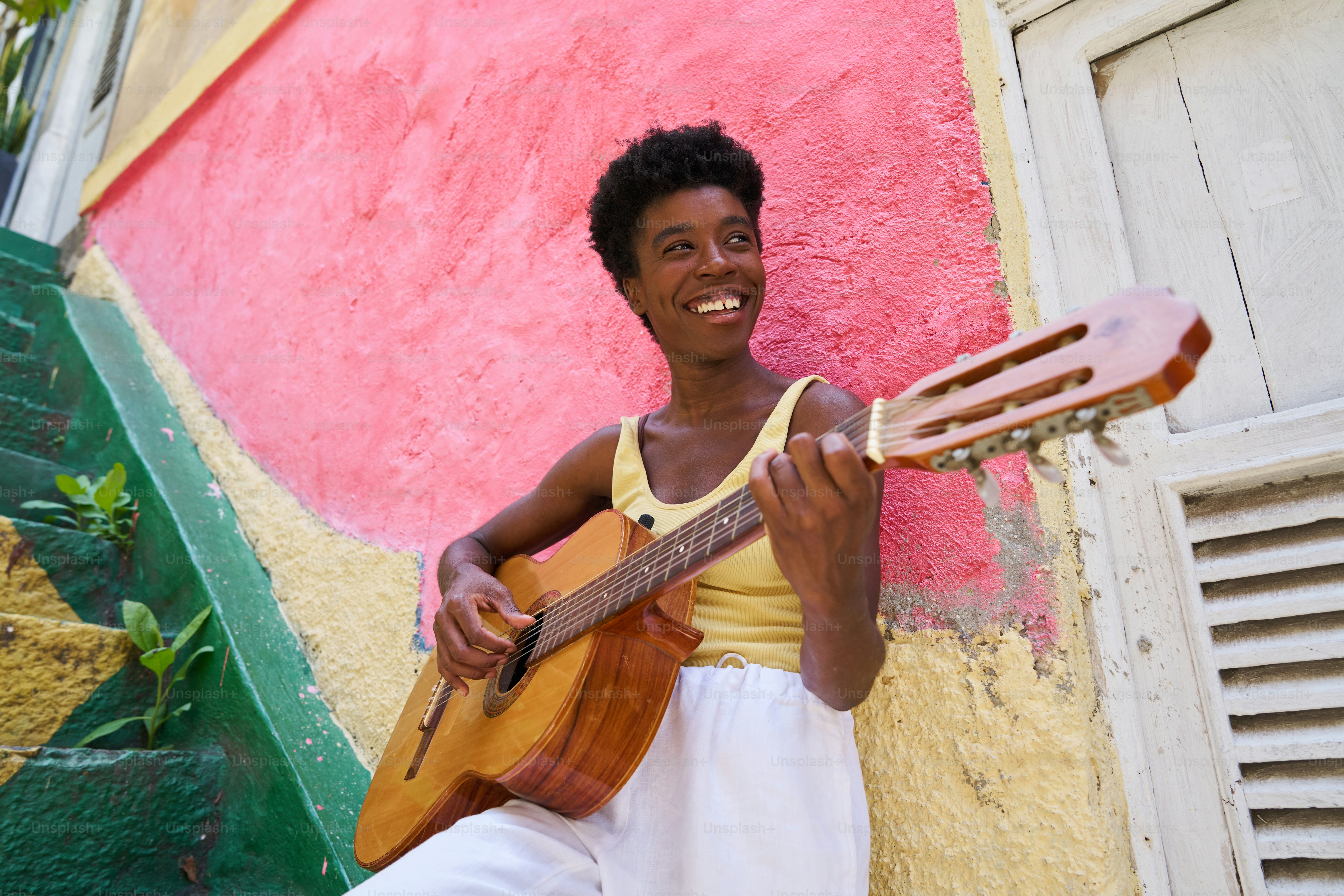 a woman playing a guitar in front of a colorful wall