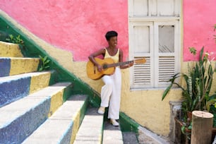 un homme assis sur des marches jouant de la guitare