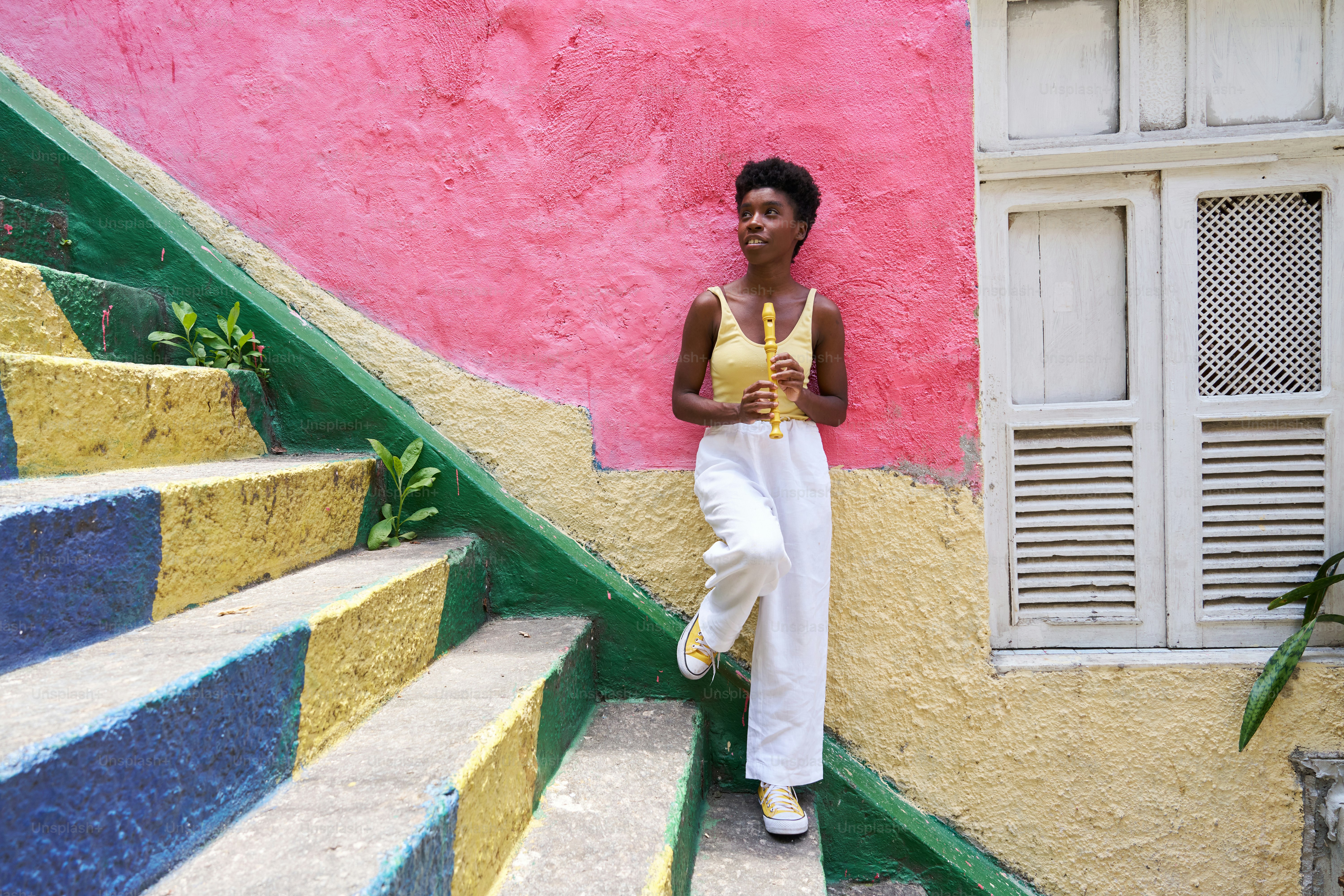 une femme appuyée contre un mur à côté d’un escalier