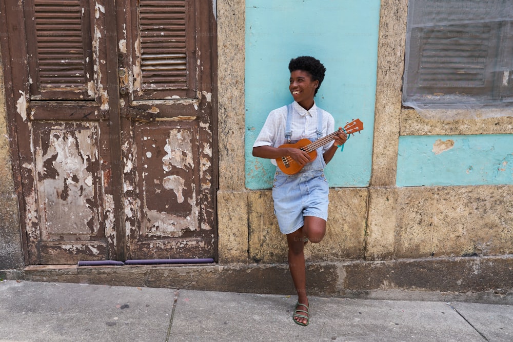 a young man is playing a guitar on the sidewalk