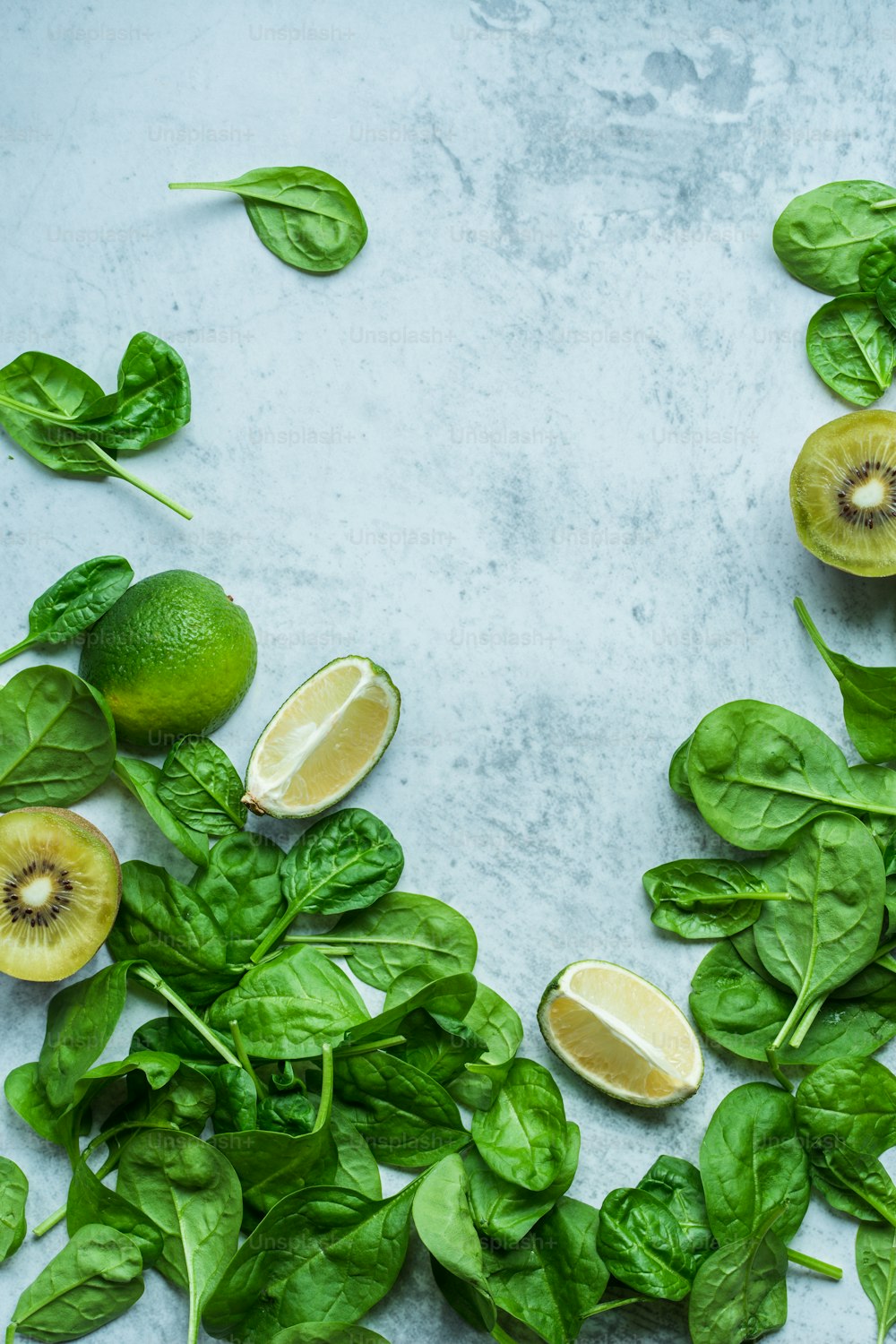 spinach leaves, lemons, and kiwis on a table