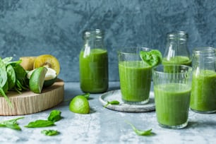 a table topped with glasses filled with green smoothies