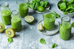 a table topped with glasses filled with green smoothies